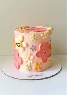 a close up of a cake on a plate with flowers and smiley face decorations in the middle