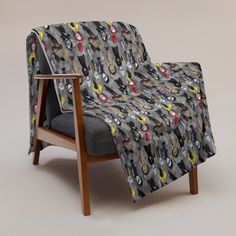 a chair with a blanket on it sitting in front of a wallpapered background