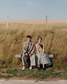 two people are sitting on a bench in the grass