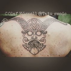 the back of a man's shoulder with an intricate tattoo design on his chest