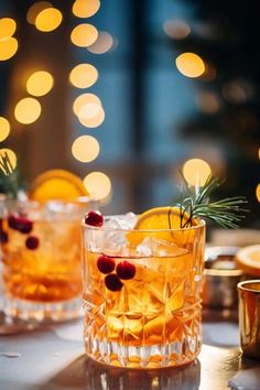 two glasses filled with drinks sitting on top of a table next to candles and plates