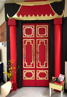 a red and black door with gold trim on the front entrance to a room filled with furniture