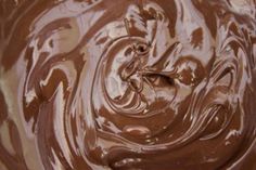 a bowl filled with chocolate frosting on top of a wooden table