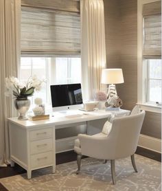 a white desk with a computer on top of it in front of two large windows