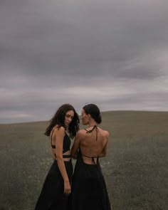 two women standing in a field with their backs turned to the camera and looking at each other