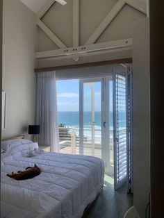 a bed sitting in a bedroom next to a sliding glass door with an ocean view