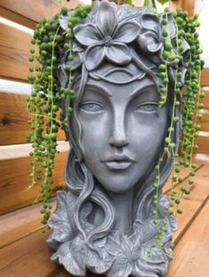 a statue is sitting on a bench with green plants growing out of it's head