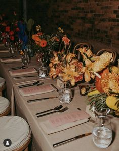 a long table with place settings and flowers in vases on the top, along with napkins