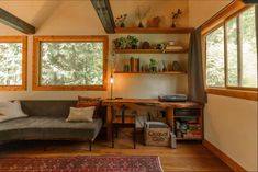 a living room filled with furniture and lots of window sill next to a desk