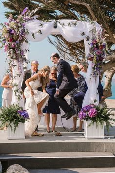 a bride and groom are standing under an arch with flowers on the altar at their wedding ceremony