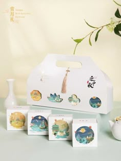 an assortment of tea bags with designs on them sitting next to a vase and pot