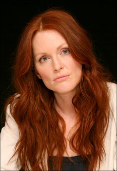 a woman with long red hair is looking at the camera