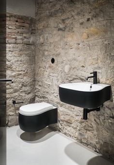 a bathroom with stone walls and black fixtures