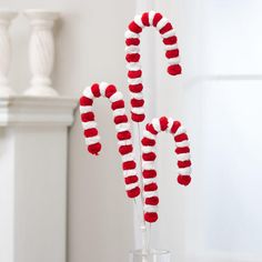 candy canes with red and white decorations in a glass vase on a wooden table