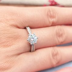 a woman's hand with a diamond ring on top of her finger and an engagement band