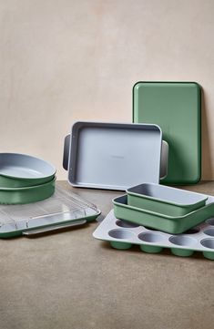 green and white kitchenware sitting next to each other on top of a brown table