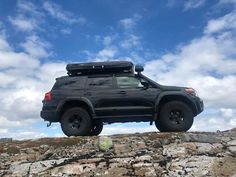 a black suv parked on top of a rocky hill