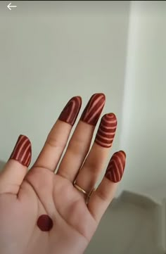 a woman's hand with red and black stripes on her nails, holding onto the tip of her fingers