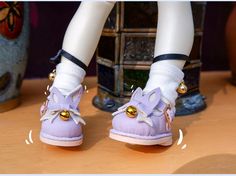 a doll's feet wearing purple shoes with gold bells on them and white socks