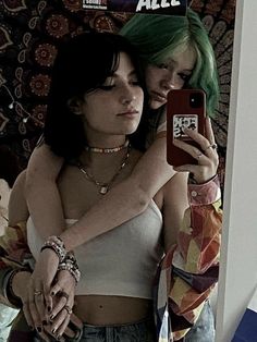 two young women taking a selfie in front of a mirror with their cell phones