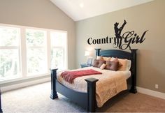 a bed room with a neatly made bed and a wall decal that says country girl