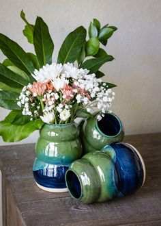 two vases with flowers in them sitting on a table