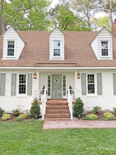 a white house with green shutters and steps leading up to the front door is shown