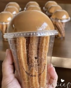 a person holding up a plastic cup filled with churros