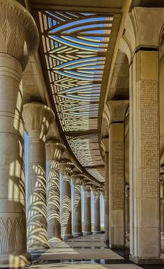 the columns are lined with intricate designs and shadows on the floor, along with other pillars