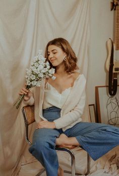 a woman sitting on a chair with flowers in her hand