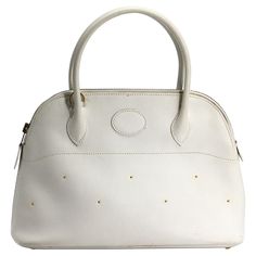 Hermes Navaho White Epsom Leather Bolide Handbag Marked in numerous places on leather and fittings. Solid white epsom leather with gold toned front and back stud details and gold toned hardware, double rounded loop handles, with white 34 in strap, zipper closure, white leather-lined interior, single interior slit. Height 11 in., Width 10 in., Depth 4 in. Condition Report Good condition, very minor interior blemishes and soiling. Navaho White, In Depth, Fashion Handbags, White Leather, Bags Handbags, Top Handle Bag, Shoe Accessories, Handles, Bag Lady