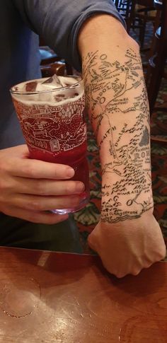 a person with a tattoo on their arm holding a drink