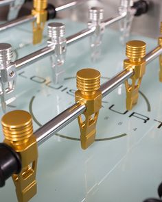 a close up view of a foosball table with gold and silver knobs