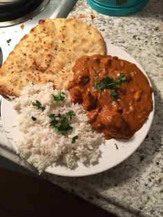 a white plate topped with rice and meat next to a flat bread on top of a counter