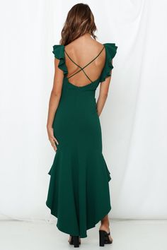 the back of a woman wearing a green dress with ruffled sleeves and open shoulders