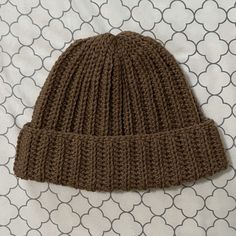 a brown knitted hat laying on top of a bed