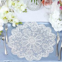 a table topped with white flowers and silverware next to a blue cloth covered table