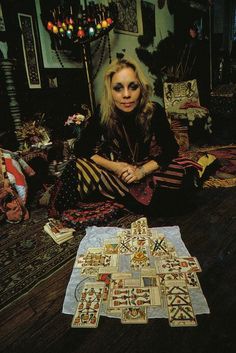 a woman sitting on the floor next to a quilt