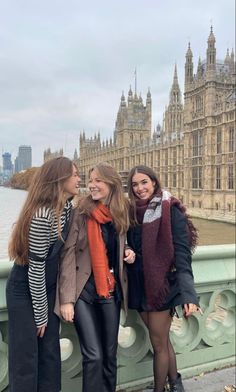 three women standing next to each other on a bridge in front of the big ben clock tower