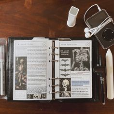 an open book sitting on top of a wooden table next to headphones and other items