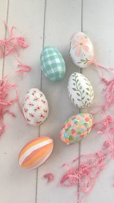 an assortment of painted eggs on a white wooden surface