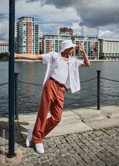 a man leaning against a pole near the water