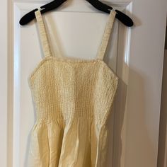 a yellow dress hanging on a white door with a black hanger in front of it