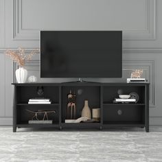 a flat screen tv sitting on top of a black entertainment center next to a vase