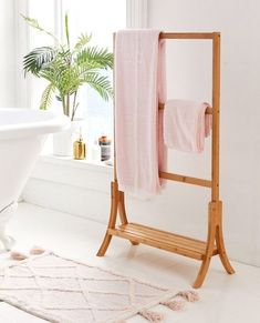 a white bath tub sitting next to a wooden stand with towels on top of it