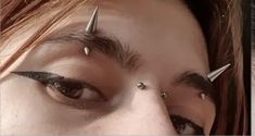 a close up of a person with piercings on their forehead and eyeliners