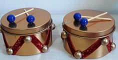 two tin canisters with wooden sticks sticking out of them and some balls on top