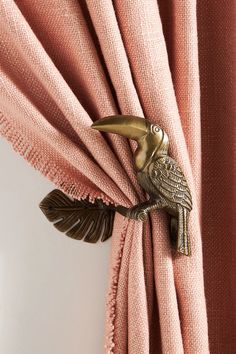 a curtain with a bird on it hanging off the side of a pink drapes