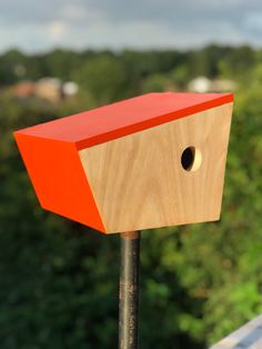 a wooden bird house on top of a roof with trees in the backgroud