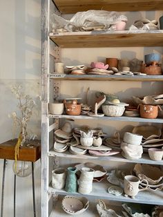 a shelf filled with lots of different types of pottery on it's sides and shelves